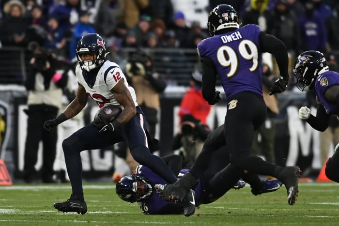 Texans wide receiver Nico Collins runs the ball against Baltimore Ravens safety Geno Stone and linebacker Odafe Oweh during the first quarter of a 2024 AFC divisional round game at M&T Bank Stadium.